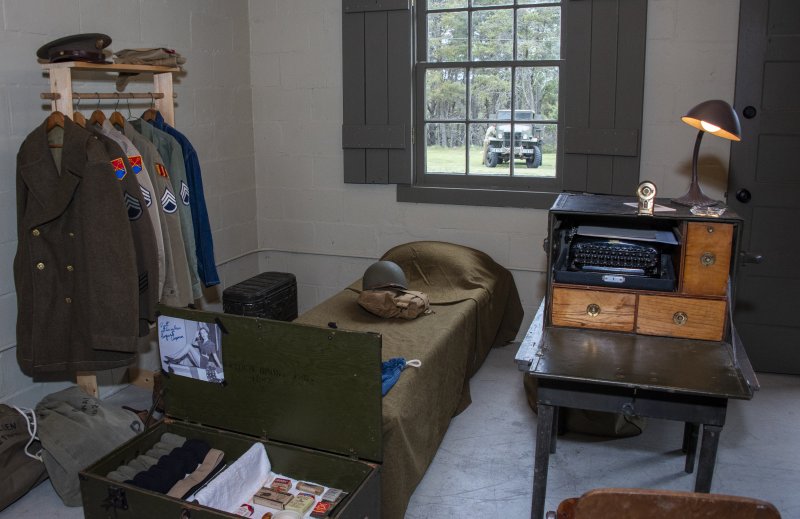 A bunk belonging to an officer, possibly a war correspondent, contains personal and work-related items.
